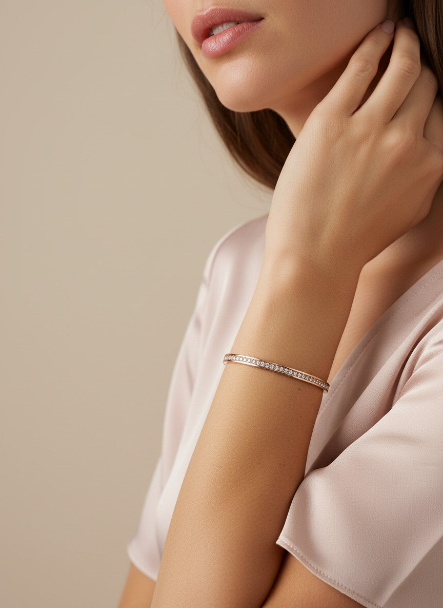 Daga-accessories rose gold bangle bracelet featuring a row of shimmering crystals worn on a woman's wrist.