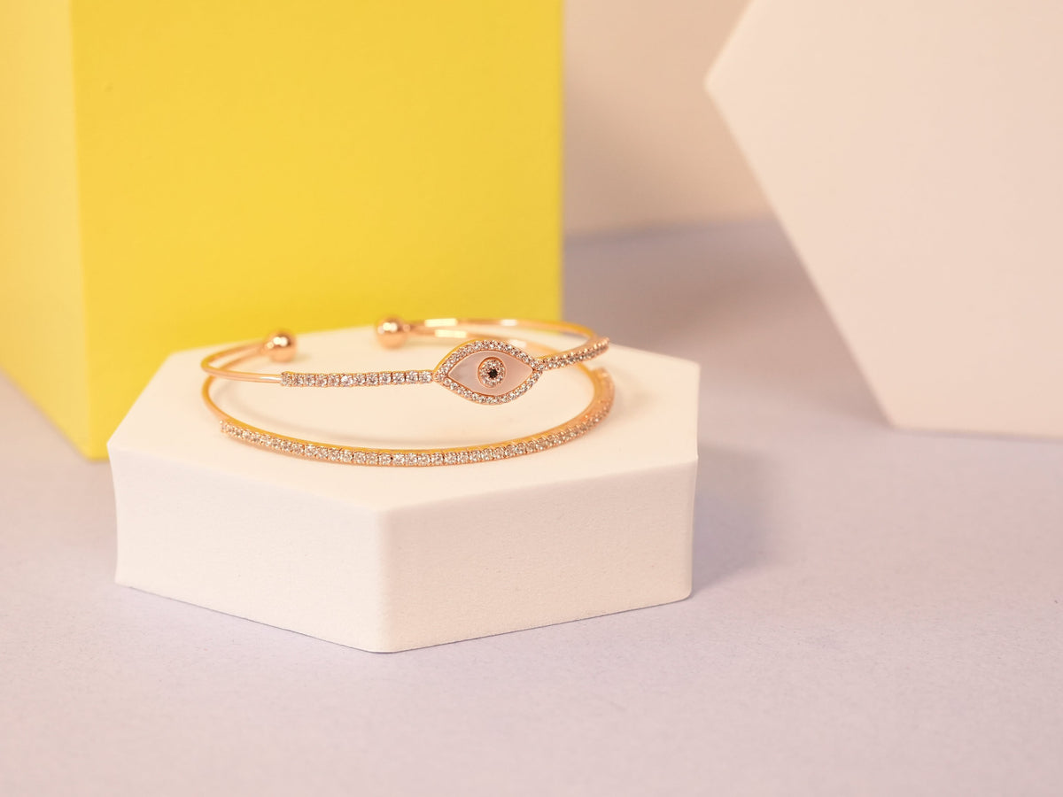 Daga-accessories rose gold evil eye cuff bracelet with delicate pavé crystal detailing on a white hexagonal stand