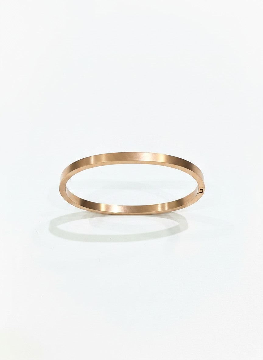 Daga-accessories minimalist rose gold-toned metal bangle bracelet with a sleek polished finish on a white background.