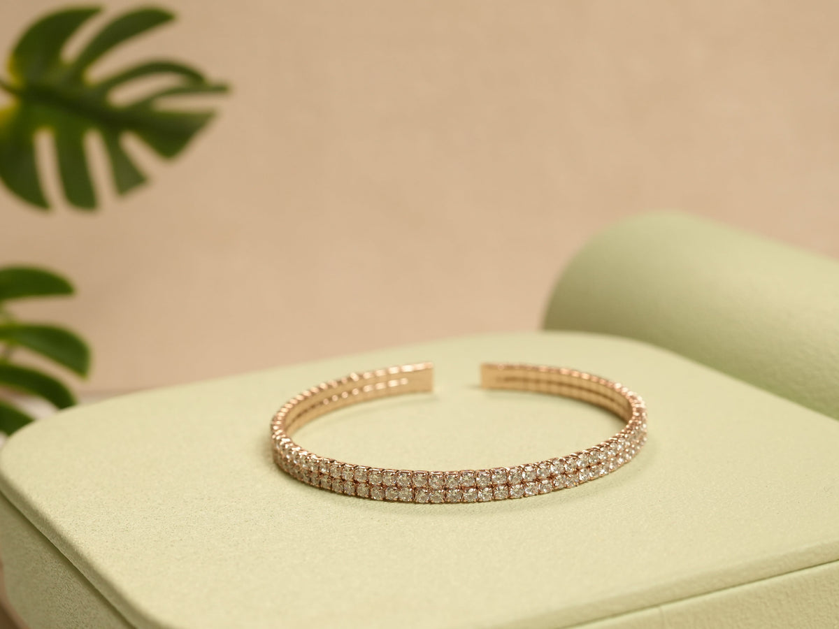 Daga-accessories rose gold two liner bracelet with sparkling studded detailing on a light green display stand.