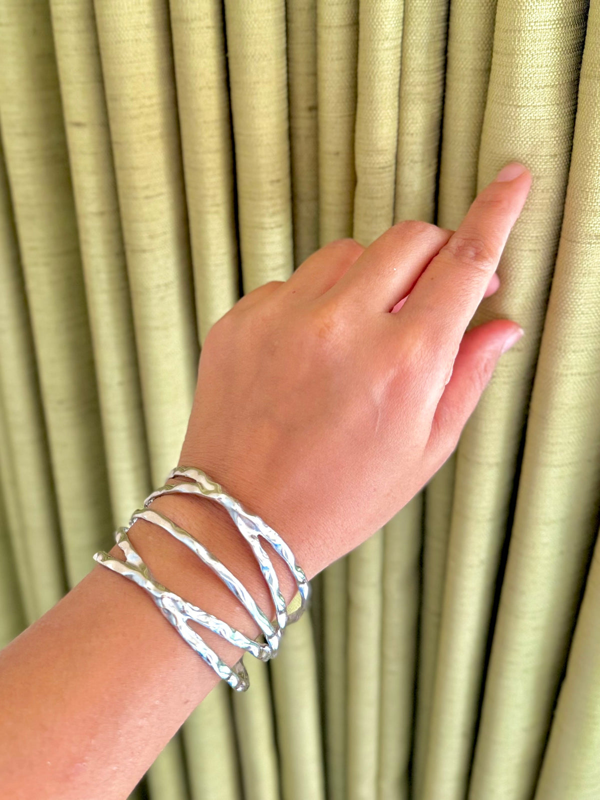 Daga-accessories silver criss cross cuff bracelet with a textured, organic finish worn on a woman's wrist