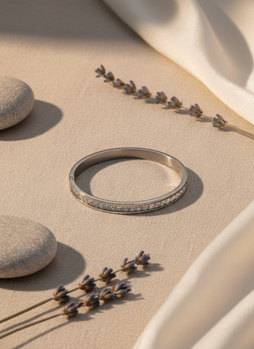 Daga-accessories silver stainless steel hinged bangle bracelet featuring a row of square-cut crystals on beige fabric