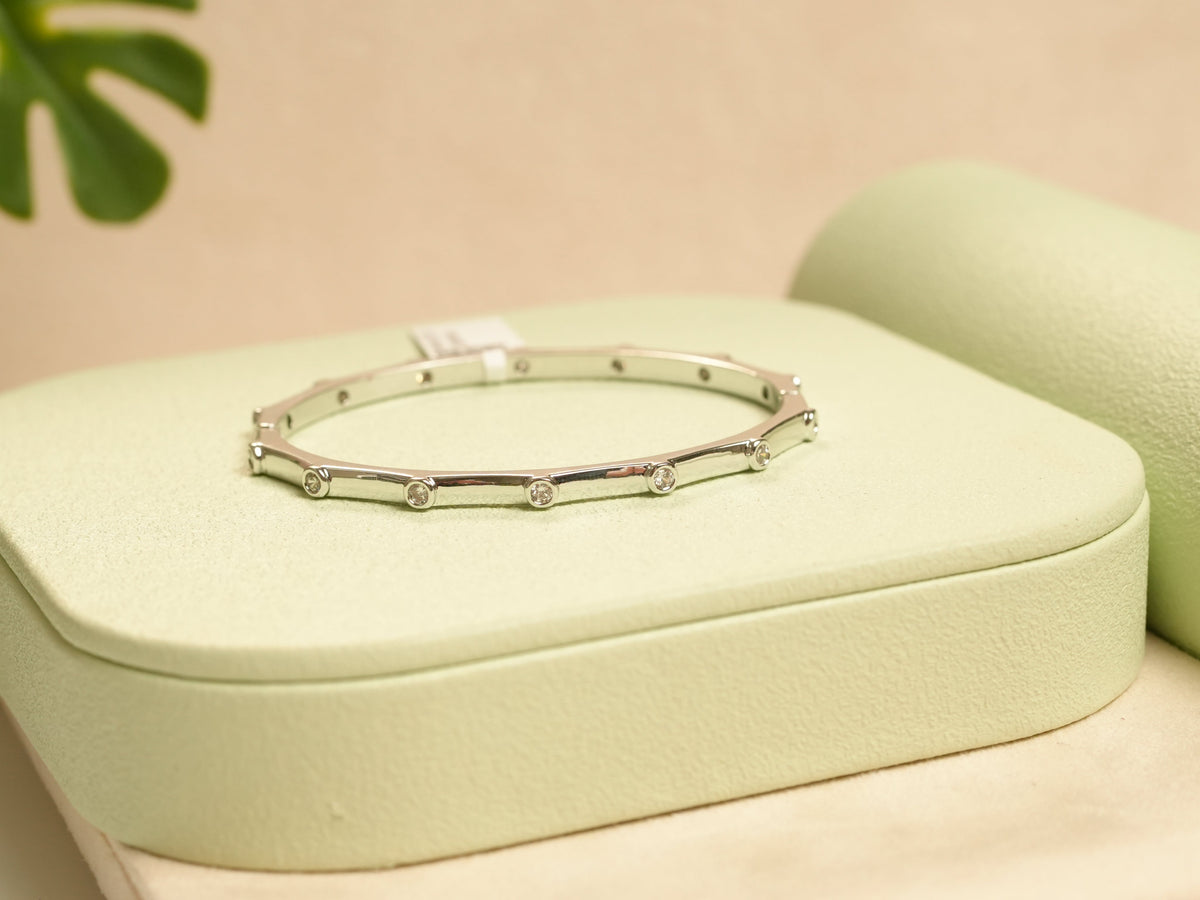 Daga-accessories silver hexagon bracelet with studded diamond detailing on a light green display stand.
