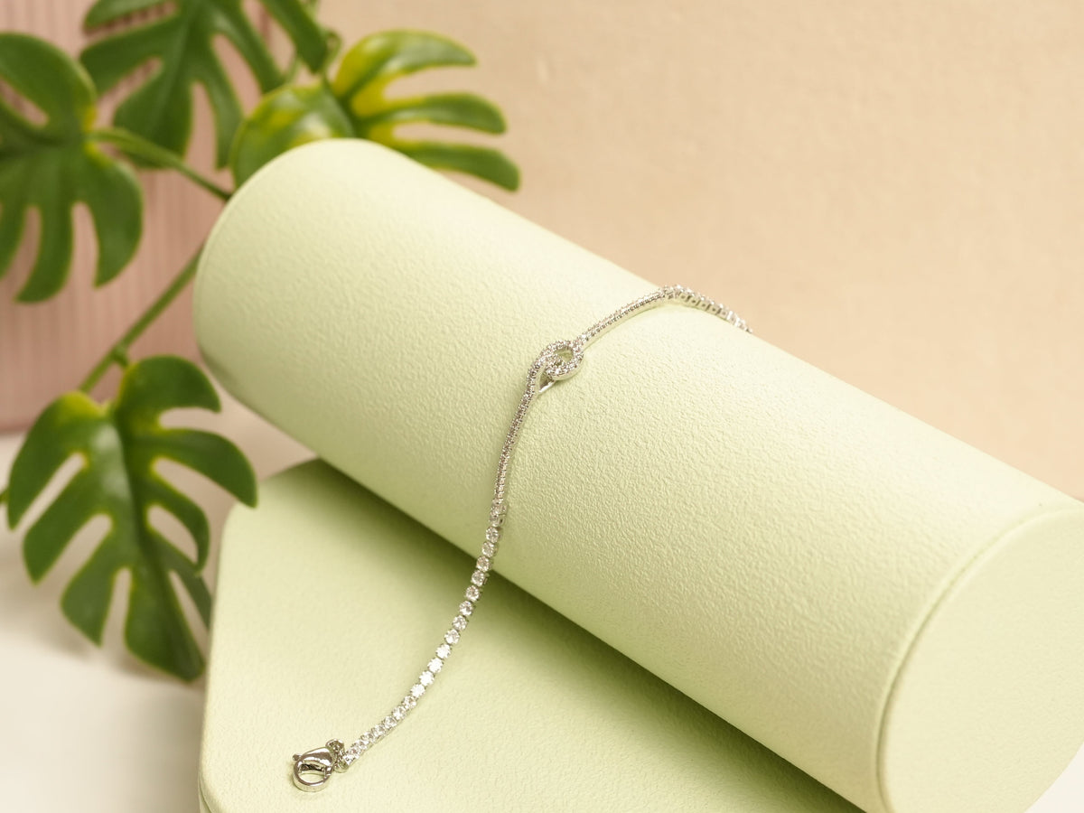 Daga-accessories silver tennis bracelet featuring delicate knotted detailing on a light green display stand.