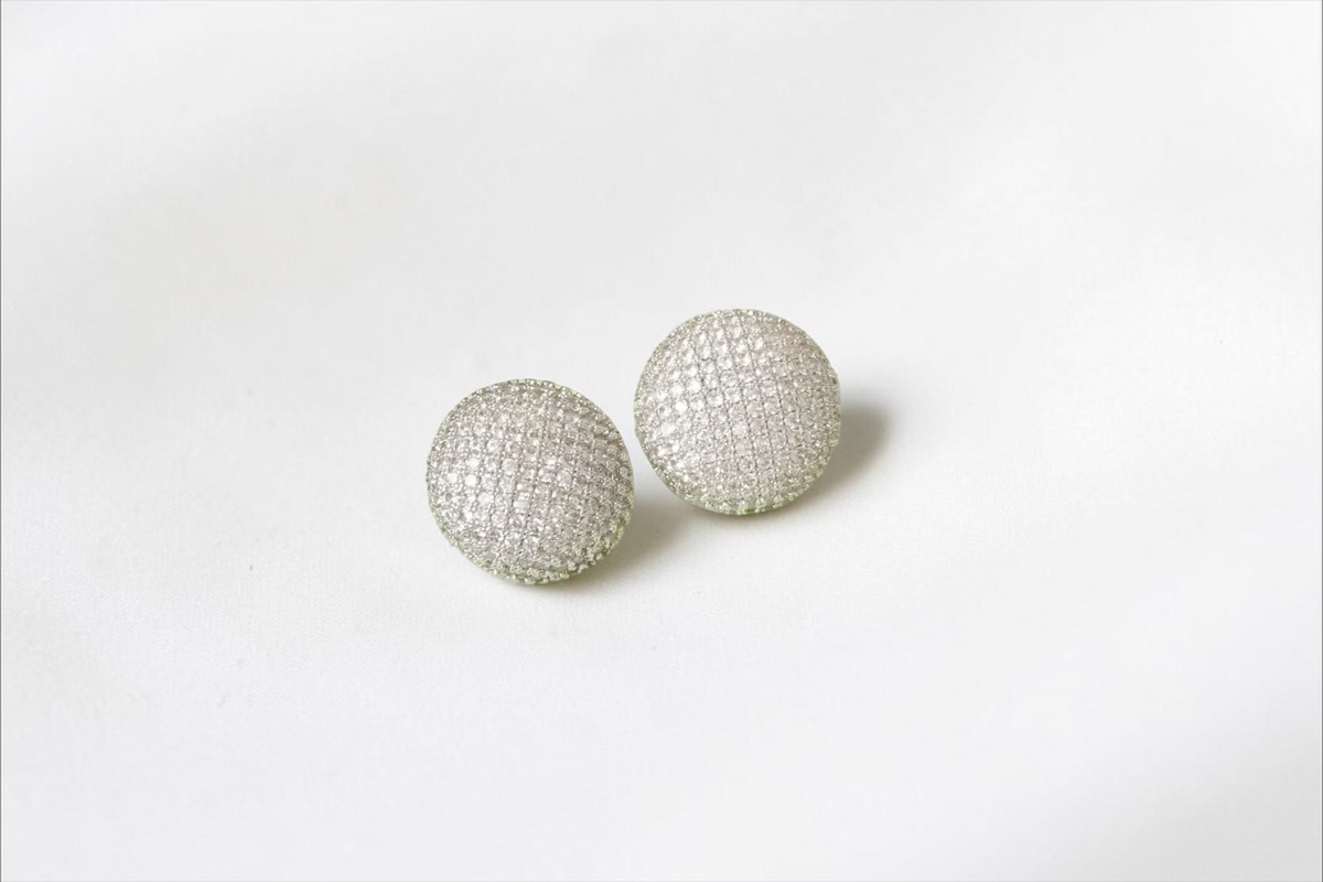 Daga-accessories silver-toned dome stud earrings with intricate pavé detailing displayed on a light green jewellery box.