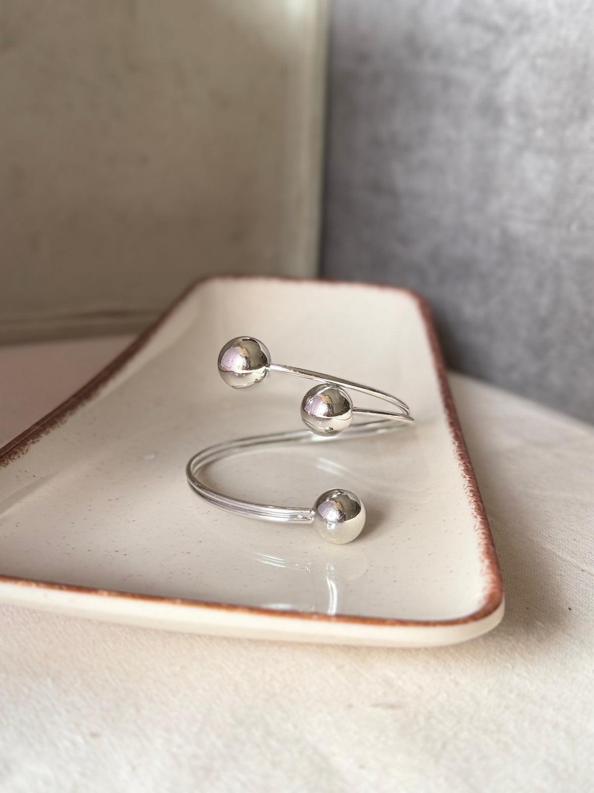 Daga-accessories silver open cuff bracelet featuring three polished spherical accents on a ceramic tray.