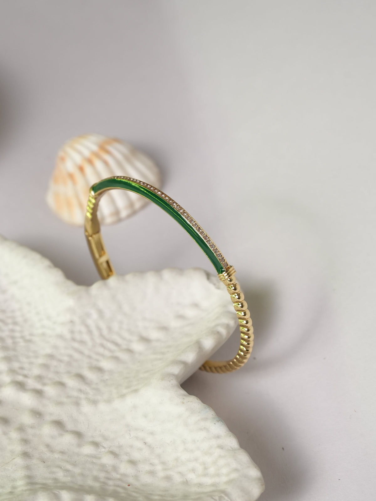 Daga-accessories slim gold-tone bracelet with green enamel inlay and delicate crystal accents on a white surface.