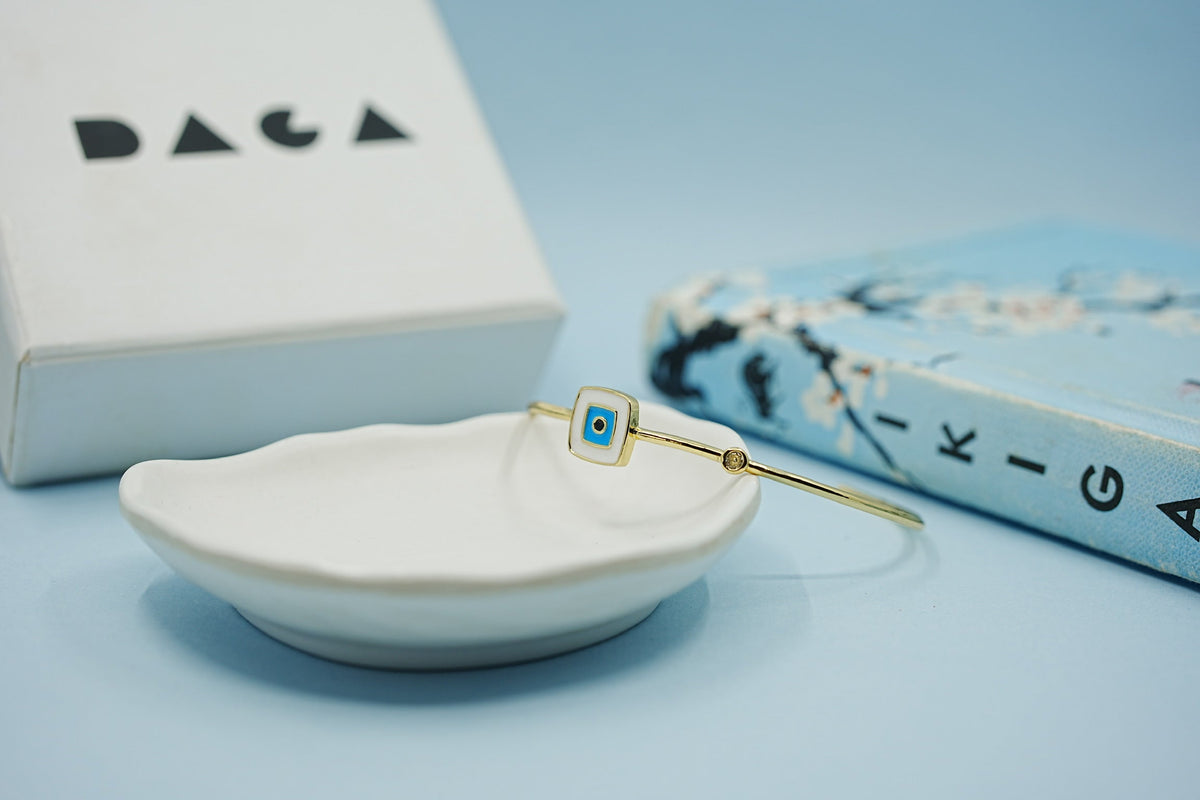 Daga-accessories gold-tone stainless steel cuff bracelet featuring a square enamel evil eye charm