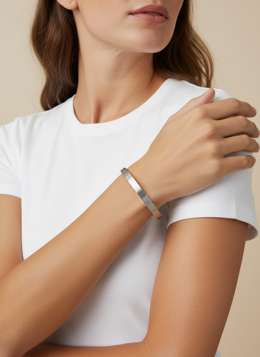 Daga-accessories minimalist stainless steel bangle with a brushed metallic finish worn on a woman's wrist