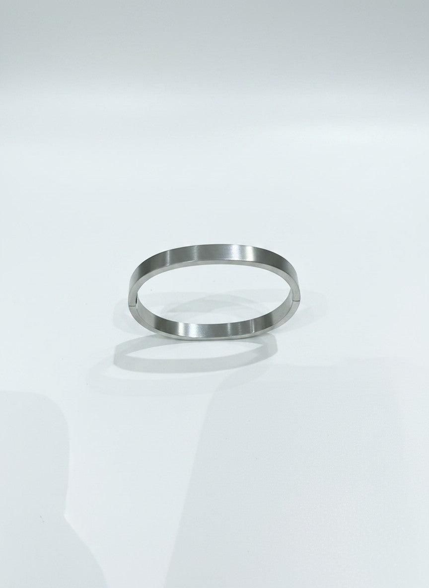 Daga-accessories minimalist silver-toned stainless steel bangle with a smooth polished finish and hinged closure.