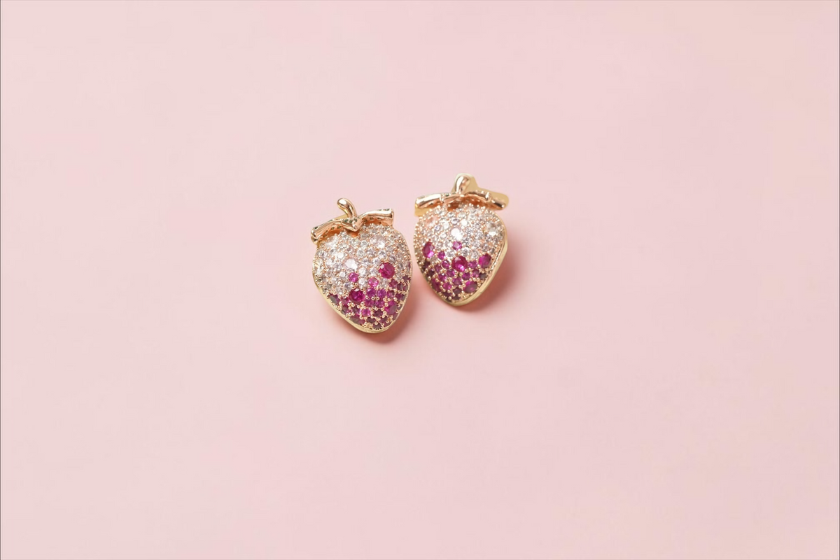 Daga-accessories strawberry stud earrings in rose gold with pink and clear cubic zirconia stones on a gold fork.