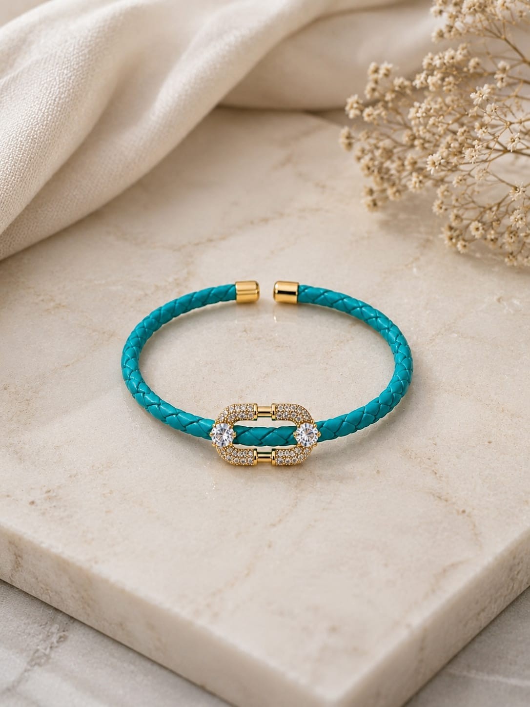 Daga-accessories teal braided leather bracelet with a gold-tone decorative clasp featuring pave-set crystals.
