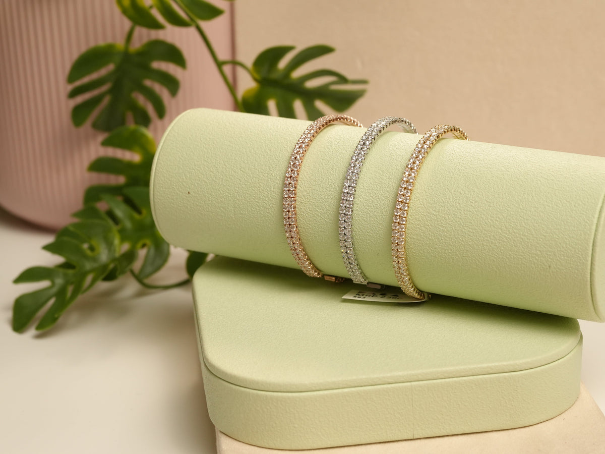 Daga-accessories gold, silver, and rose gold two liner bracelets with studded detailing on a light green display