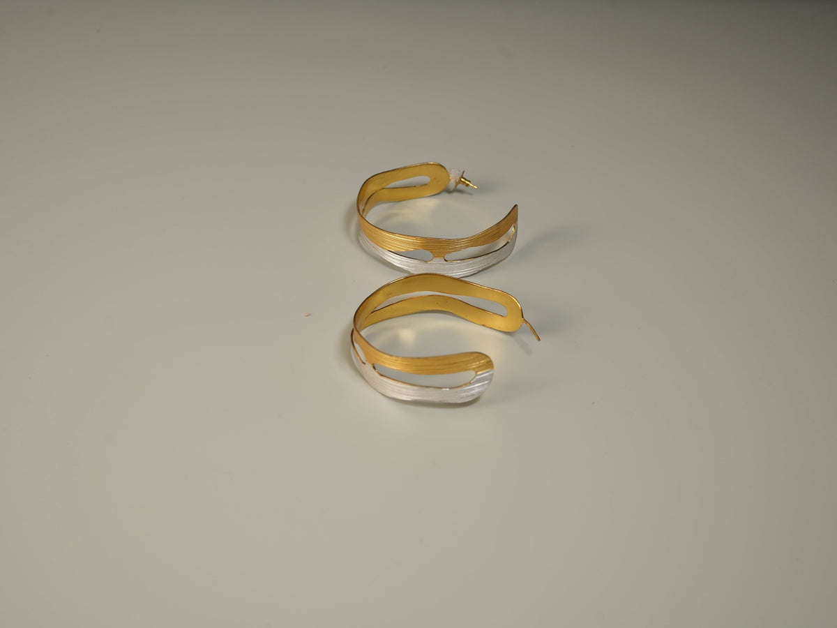 Daga-accessories two-tone layered hoop earrings featuring brushed gold and silver metal textures.