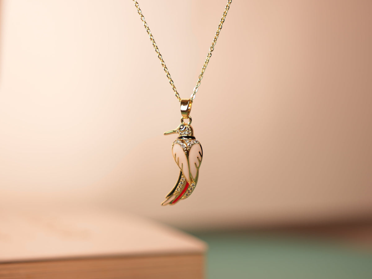 Daga-accessories Canary Song necklace featuring a white enamel bird pendant with gold accents and sparkling crystals.