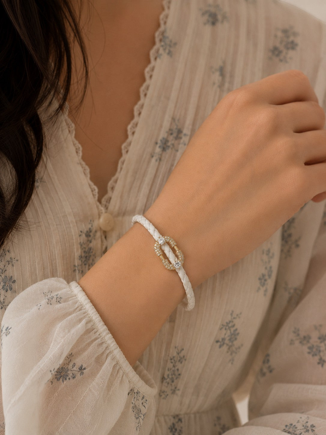 Daga-accessories white braided leather bracelet featuring a crystal-encrusted oval link clasp on a woman's wrist