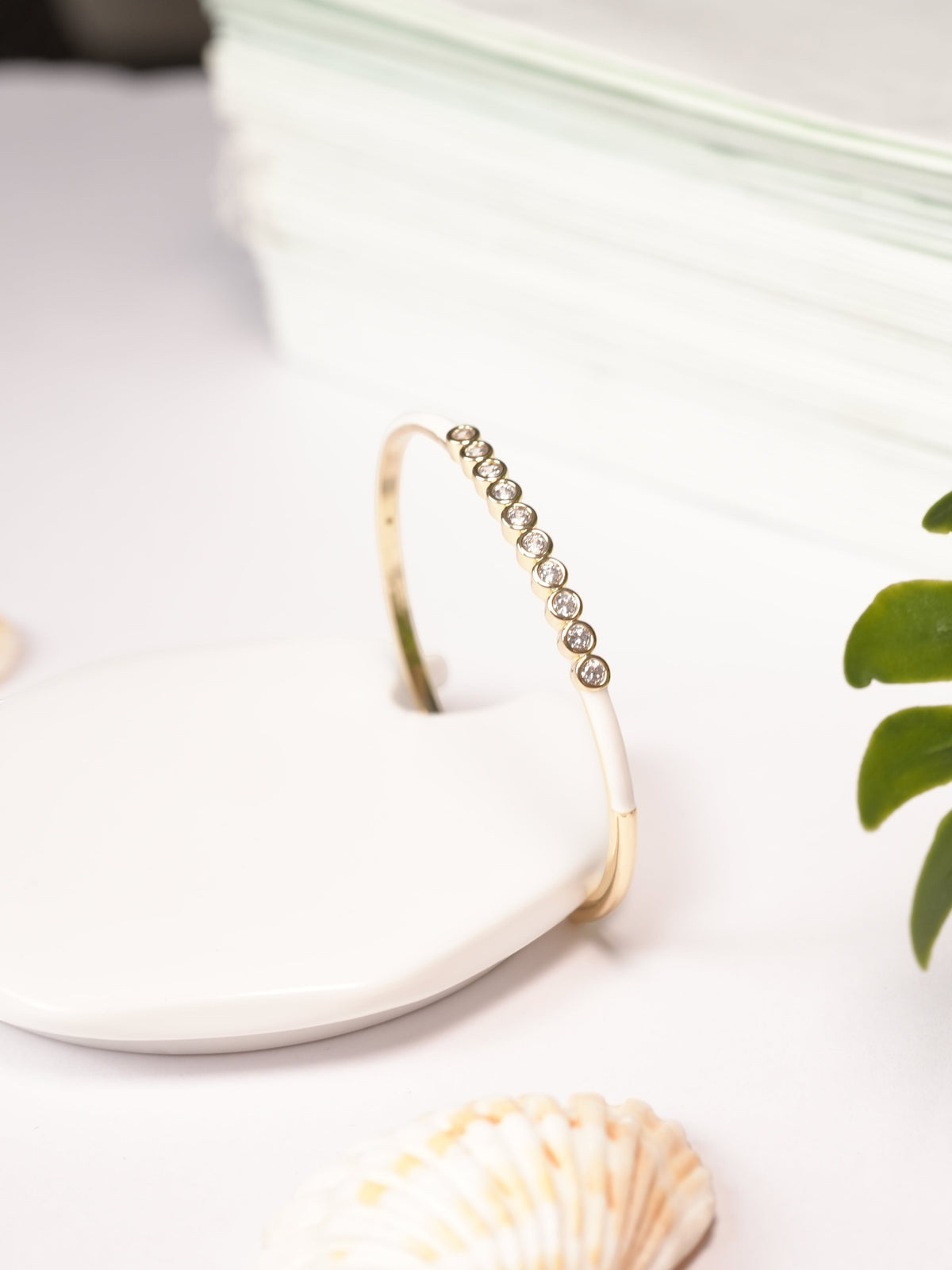 Daga-accessories white dotted crystal bracelet with gold-tone band and precision-cut stones on a white display stand.
