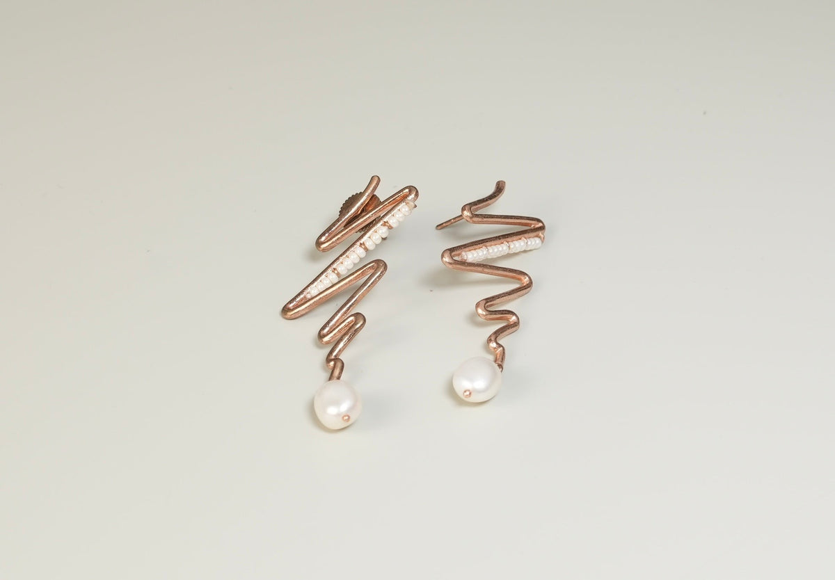 Daga-accessories Zigzag pearl earrings featuring a wavy rose gold design with small white pearls on a light background